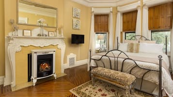 A bedroom with a fireplace, a bed with a canopy, and a television.
