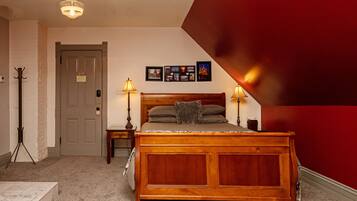 A bedroom with a wooden bed, two bedside lamps, a door, and a wall with framed pictures.