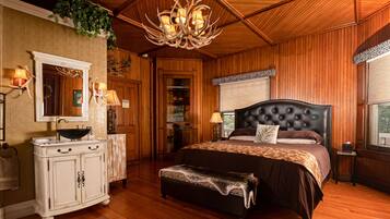 Ein Zimmer mit Holzboden, einem großen Bett mit gestepptem Kopfteil, einer weißen Kommode mit Spiegel und einer Kristallleuchtreiter.