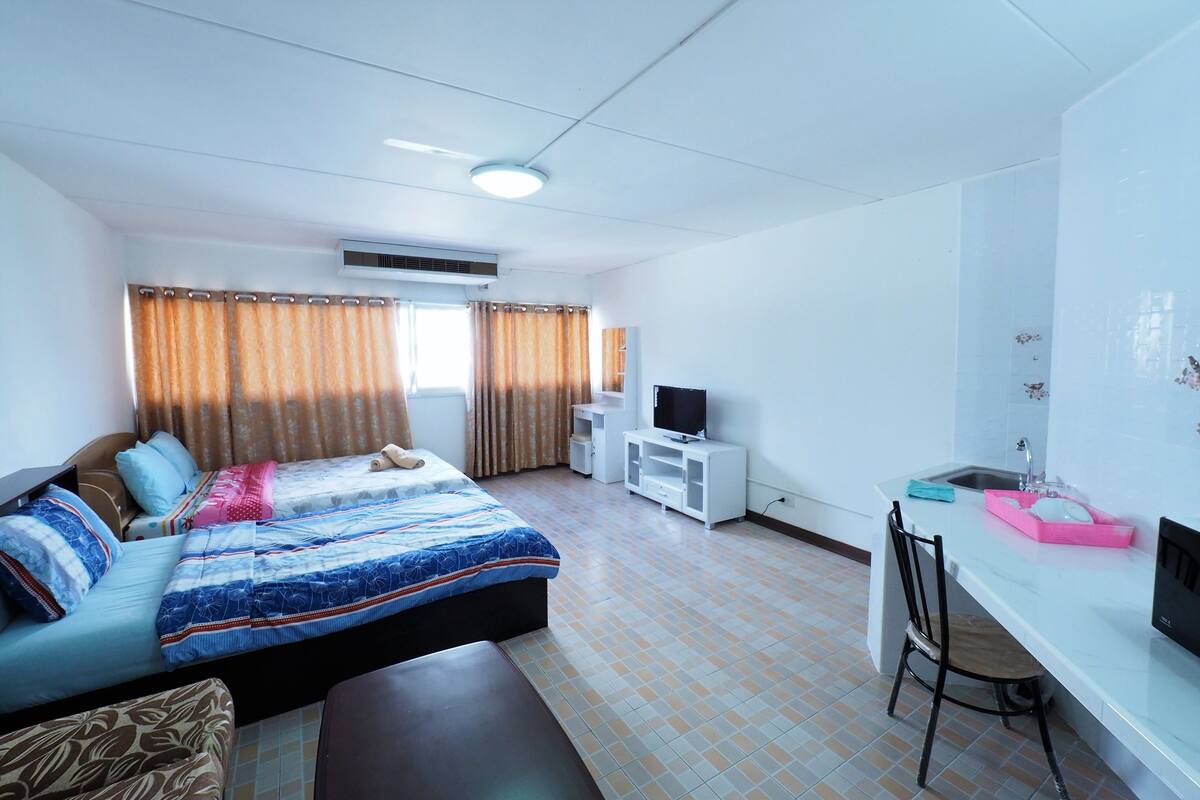 Ein Hotelzimmer mit Bett, Schreibtisch, Stuhl, Fernseher und einem Fenster mit Vorhängen.