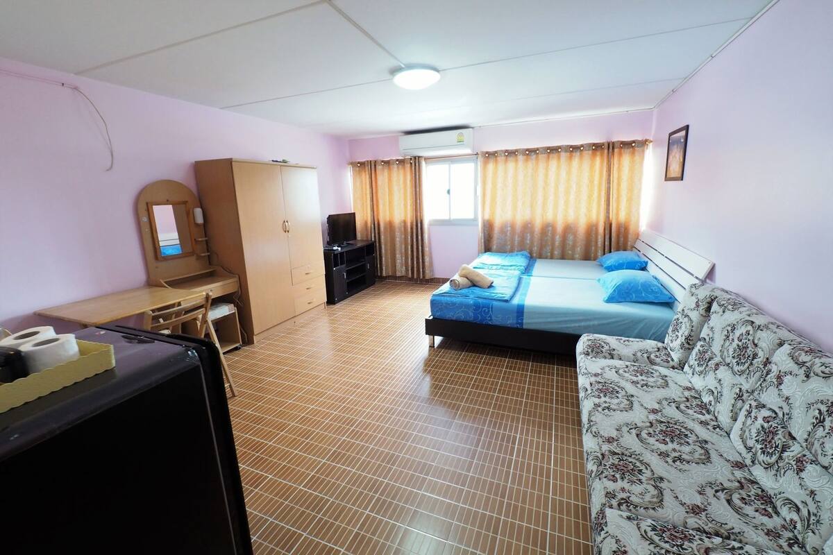 Ein Hotelzimmer mit einem Bett, einer Schlafcouch, einem Schreibtisch, einem Fernseher und einem Kleiderschrank.