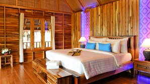 Un dormitorio tipo cabaña de madera con una cama grande, paredes de madera y una ventana con cortinas.