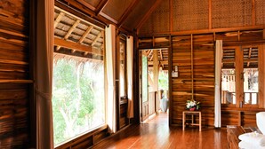 Interior de madera con ventanas amplias, un banco de madera y una pequeña mesa con un florero.