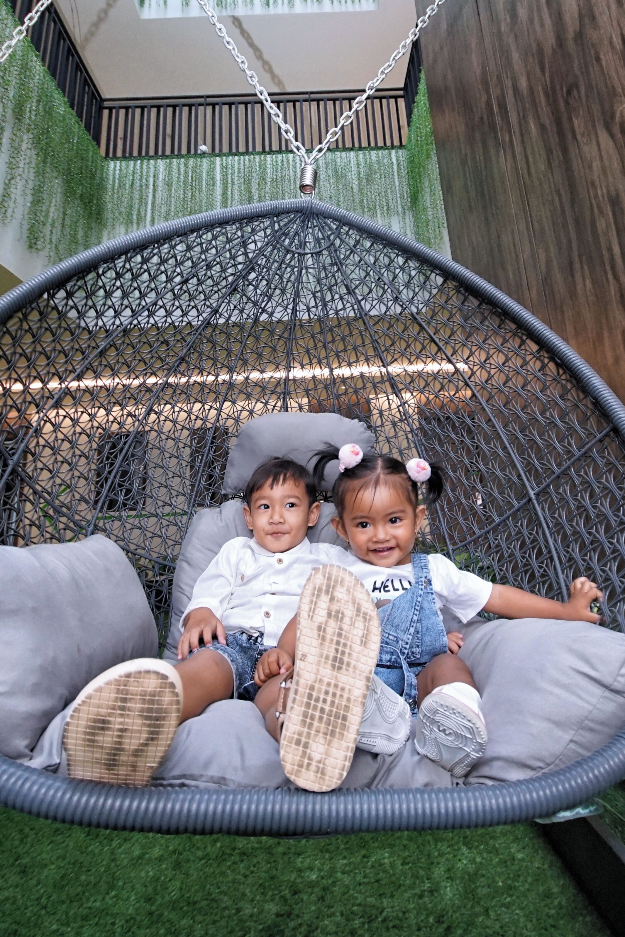 A hanging chair with a mesh design, grey cushions, and a grey rope.