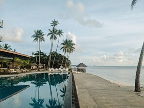 Una piscina con palmeras y vista al mar.