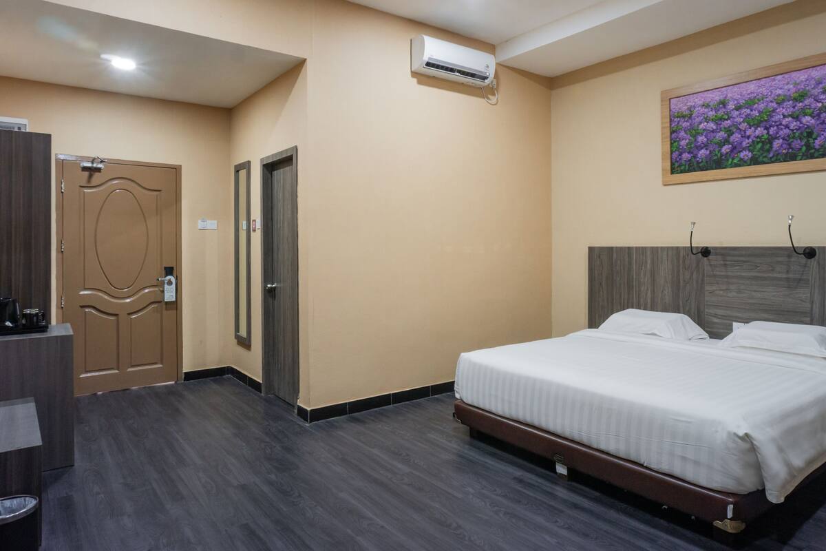 Ein Hotelzimmer mit Bett, Nachttisch und einem Blumenbild an der Wand.