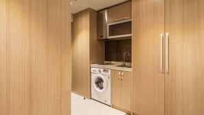 A compact kitchen with wooden cabinets, a built-in washing machine, and a stainless steel range hood.