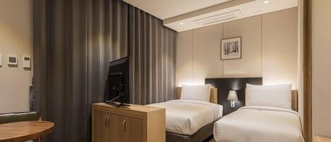 A hotel room with two beds, a desk, a television, and a cabinet.