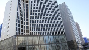 A modern high-rise building with a grid of windows and a glass facade at the base.