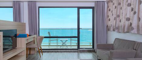 Una habitación de hotel moderna con balcón, televisión de pantalla plana, sofá y zona de comedor.