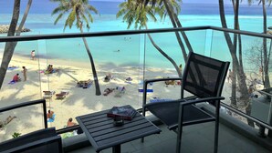 A beach view from a balcony with palm trees, a pool table, and lounge chairs. - Kaani Grand Seaview (Maafushi)