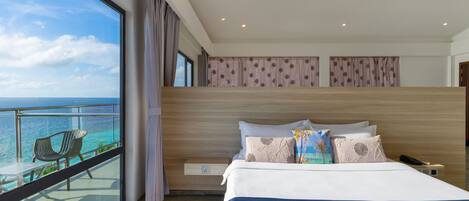 Habitación de hotel con una cama grande, vistas al océano y un balcón con sillas.
