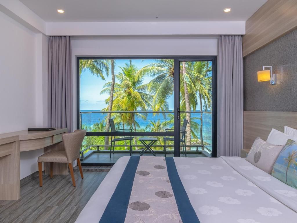 Una habitación de hotel con un ventanal grande, una cama, un escritorio y una silla.