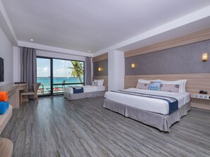 Habitación de hotel con una cama grande, una cama más pequeña, un escritorio y vistas al océano.