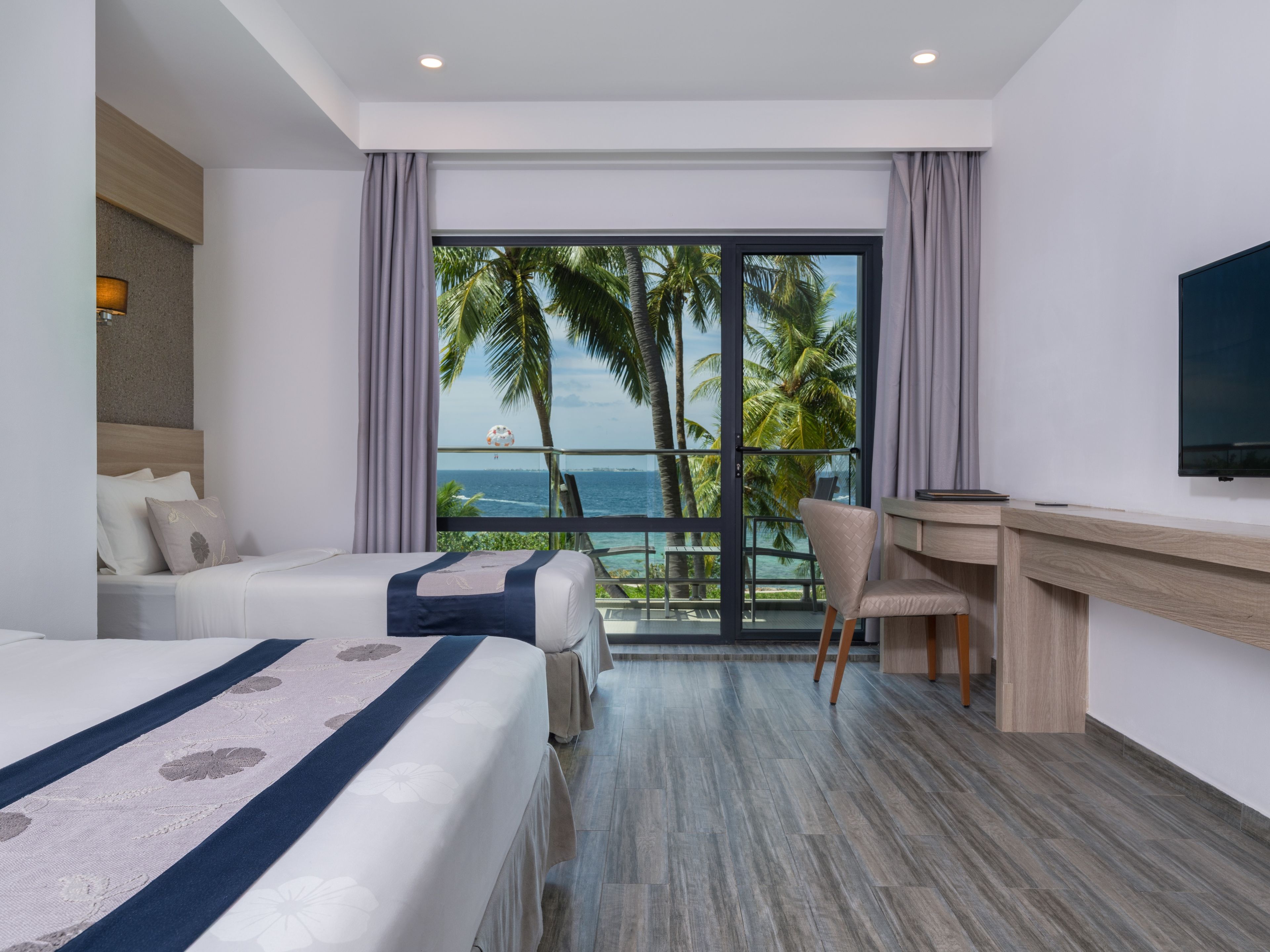 A hotel room with a bed, a desk, and a view of the ocean.
