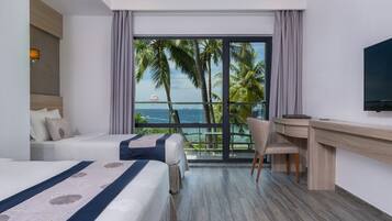 A hotel room with a bed, a desk, and a view of the ocean.