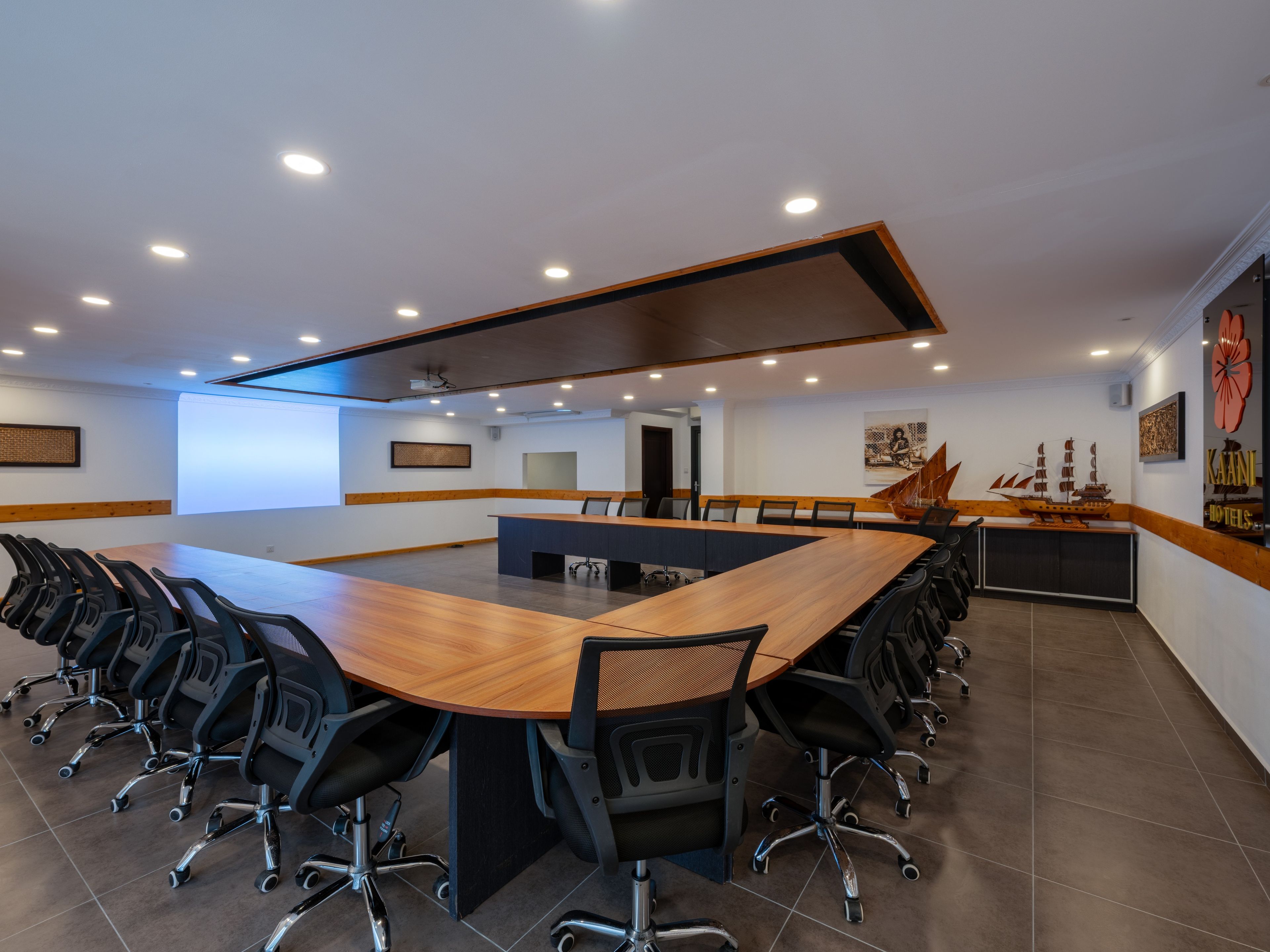 A conference room with a long table, multiple chairs, and a modern ceiling design.