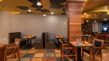 A restaurant interior with wooden furniture, tiled flooring, and decorative ceiling elements.