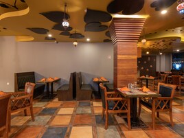 Interior de un restaurante con mobiliario de madera, suelo de baldosas y detalles decorativos en el techo.