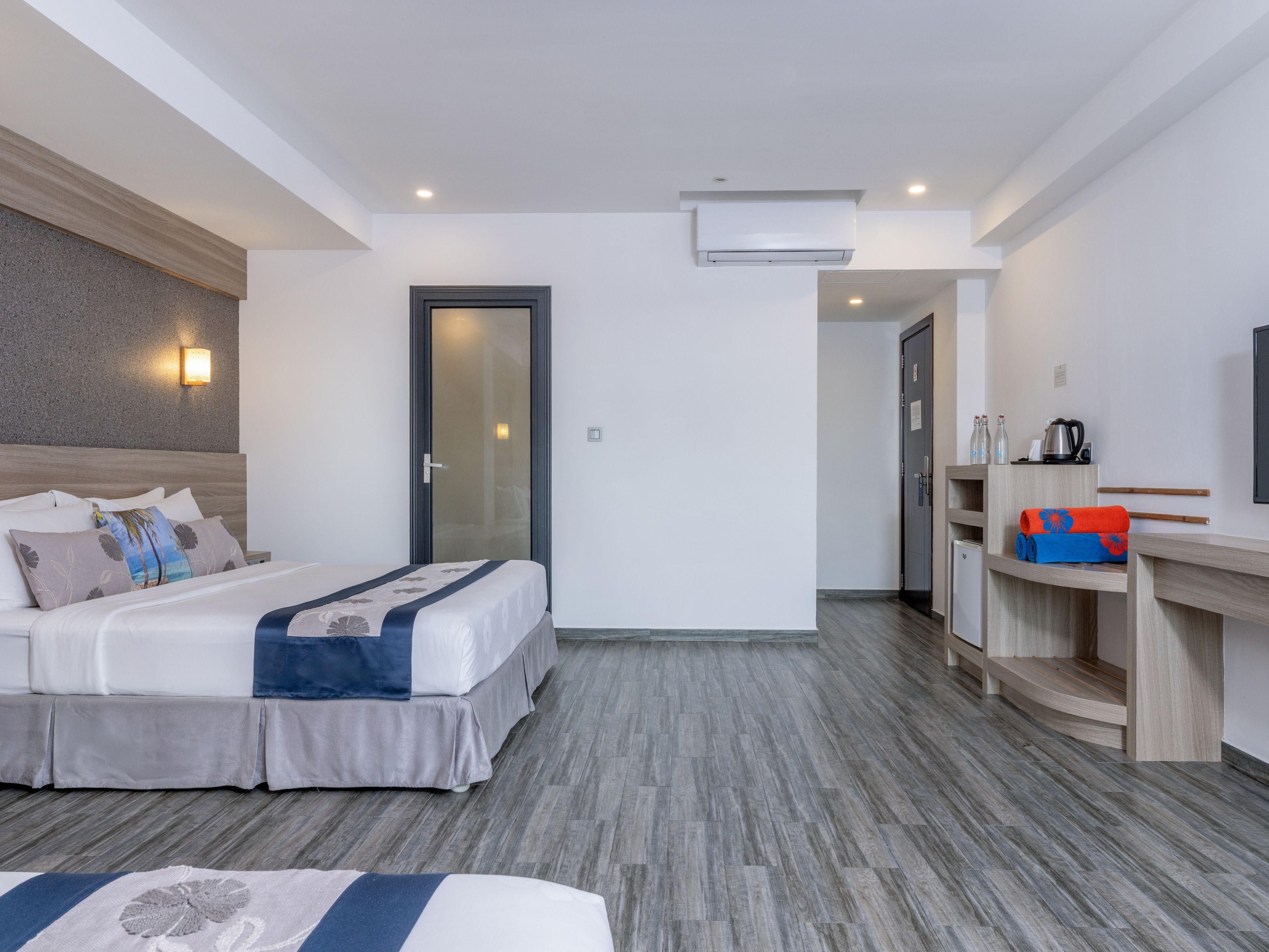 A hotel room with a bed, bedside table, and a small kitchenette area.