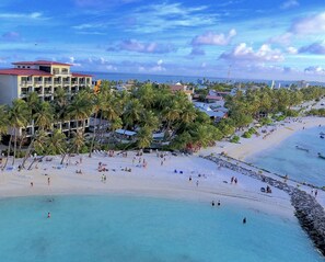A beach resort with a large building, palm trees, and a sandy beach. - Kaani Grand Seaview (Maafushi)