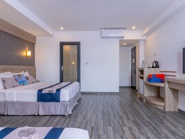 Una habitación de hotel con cama, mesita de noche y una pequeña zona de kitchenette.