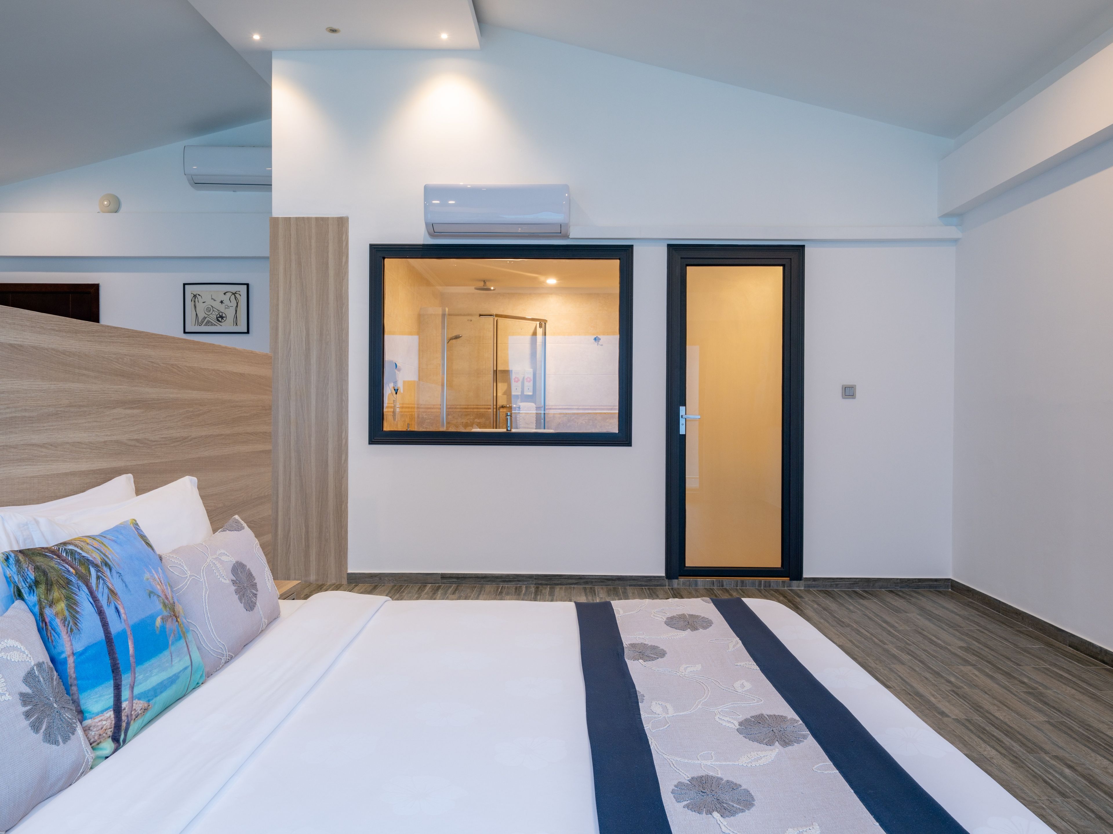 Una habitación de hotel con cama, zona de ducha y puerta que da a un baño.