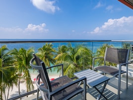 Un balcón con vista al océano, palmeras y una playa.