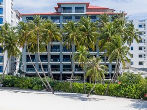A multi-story hotel with balconies, surrounded by palm trees and a sandy beach. - Kaani Grand Seaview (Maafushi)