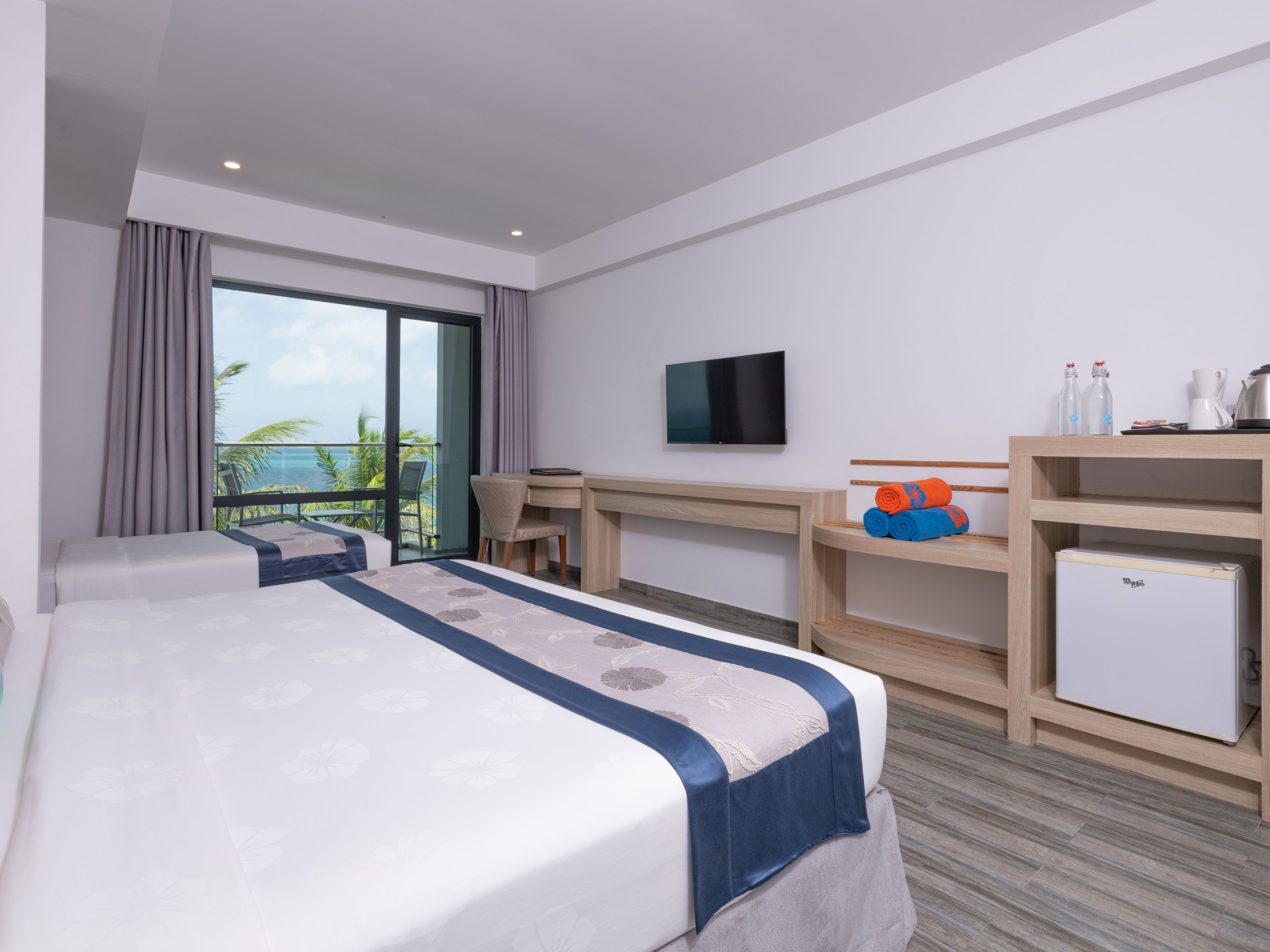 Una habitación de hotel con cama, escritorio, televisión y vista al océano.