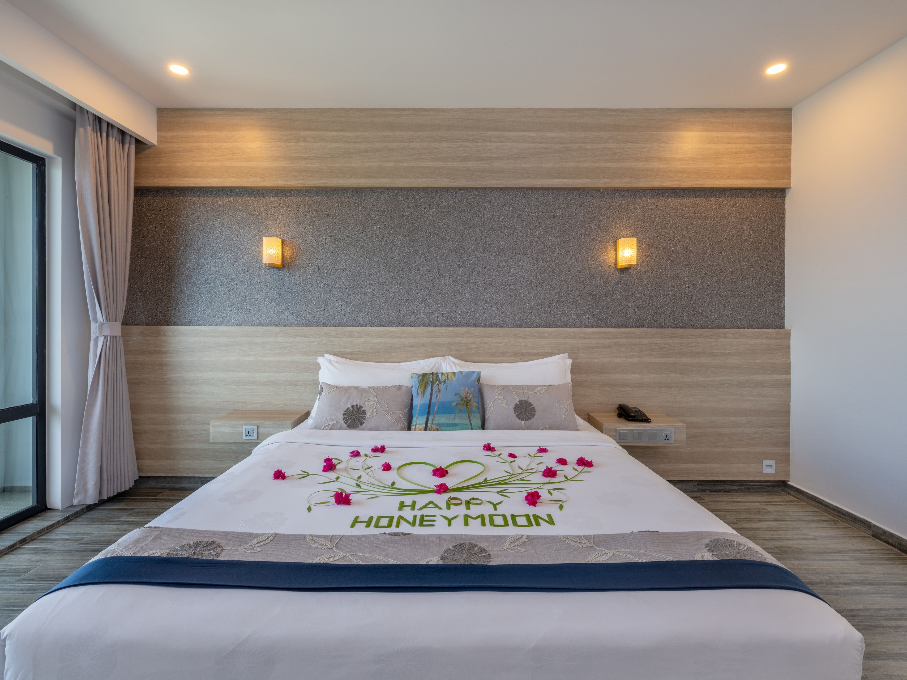 A hotel room with a bed, bedside table, and a nightstand.