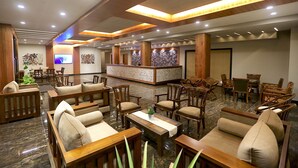 A spacious lobby with wooden furniture, a reception desk, and a television screen. - Kaani Grand Seaview (Maafushi)