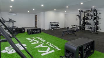 Un gimnasio con equipo de ejercicio, una zona de césped artificial verde y un soporte de mancuernas fijado a la pared.