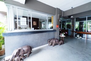 A reception area with a counter, a large window, and a potted plant. - Namnon Place (Nonthaburi)