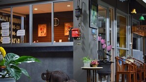 A restaurant with a large window, a small table with plants, and a decorative elephant sculpture outside. - Namnon Place (Nonthaburi)
