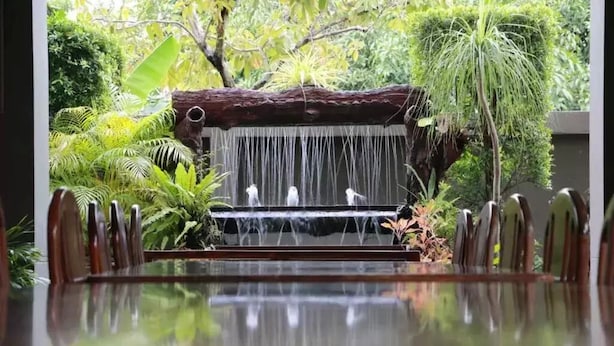 A dining area with a waterfall feature, surrounded by lush greenery. - Namnon Place (Nonthaburi)