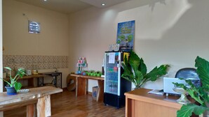 A room with a wooden floor, a refrigerator, a table with a plant, and a wall with a map and a sign. - Beji Ayu Homestay (Seminyak)