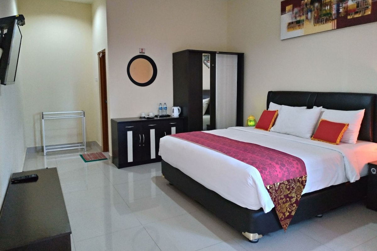 A hotel room with a bed, a wardrobe, a desk, and a mirror.