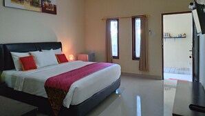 A hotel room with a large bed, a bedside table, an air conditioning unit, and a view of the outside through a window. - Beji Ayu Homestay (Seminyak)