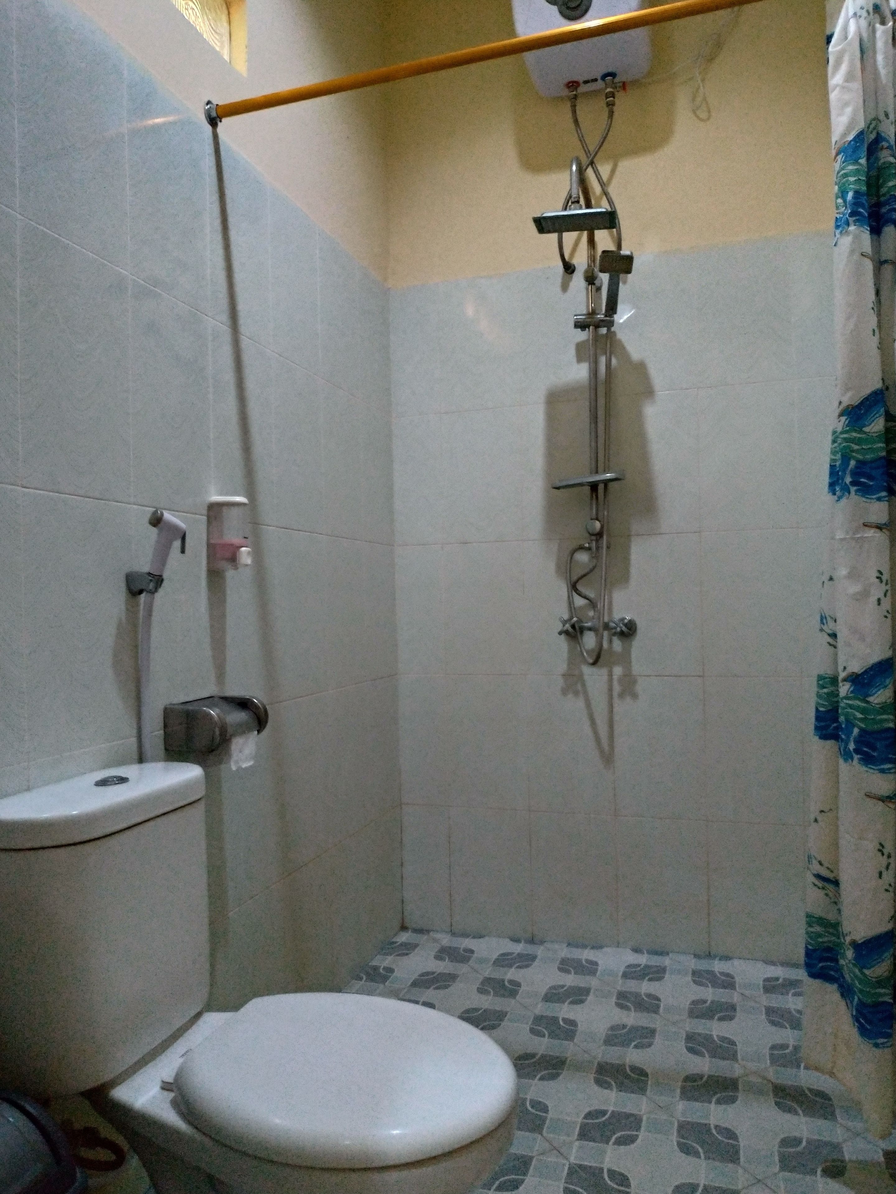 A small bathroom with a toilet, a shower, and a patterned floor.