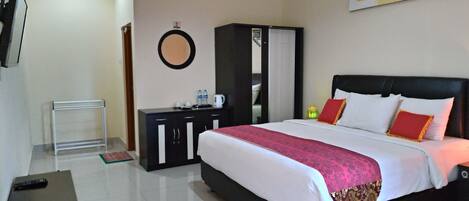 Una habitación de hotel con cama, armario, escritorio y espejo.