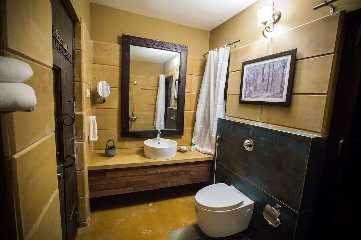 A bathroom with a wooden vanity, a white sink, a large mirror, a white toilet, and a shower curtain.