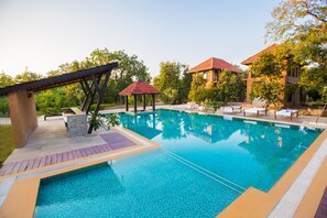 A swimming pool with lounge chairs and a gazebo. - Vannraj Resort and Spa (Kurai)