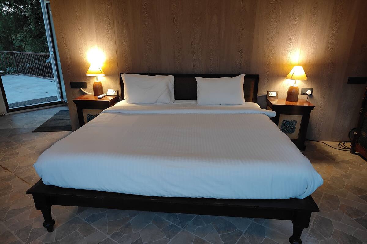 A large bed with white linens, two bedside tables with lamps, and a wooden headboard.