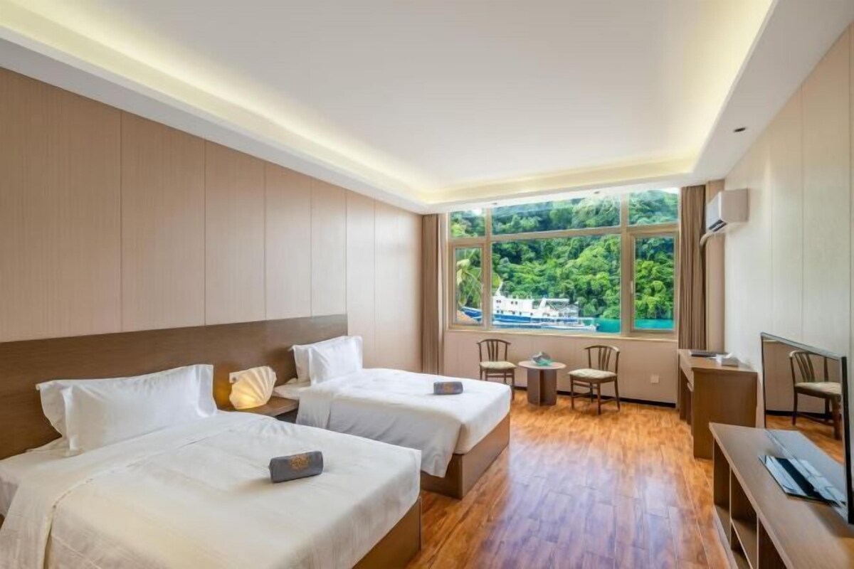 Une chambre d’hôtel avec deux lits, un bureau, une chaise et une vue sur un lac.