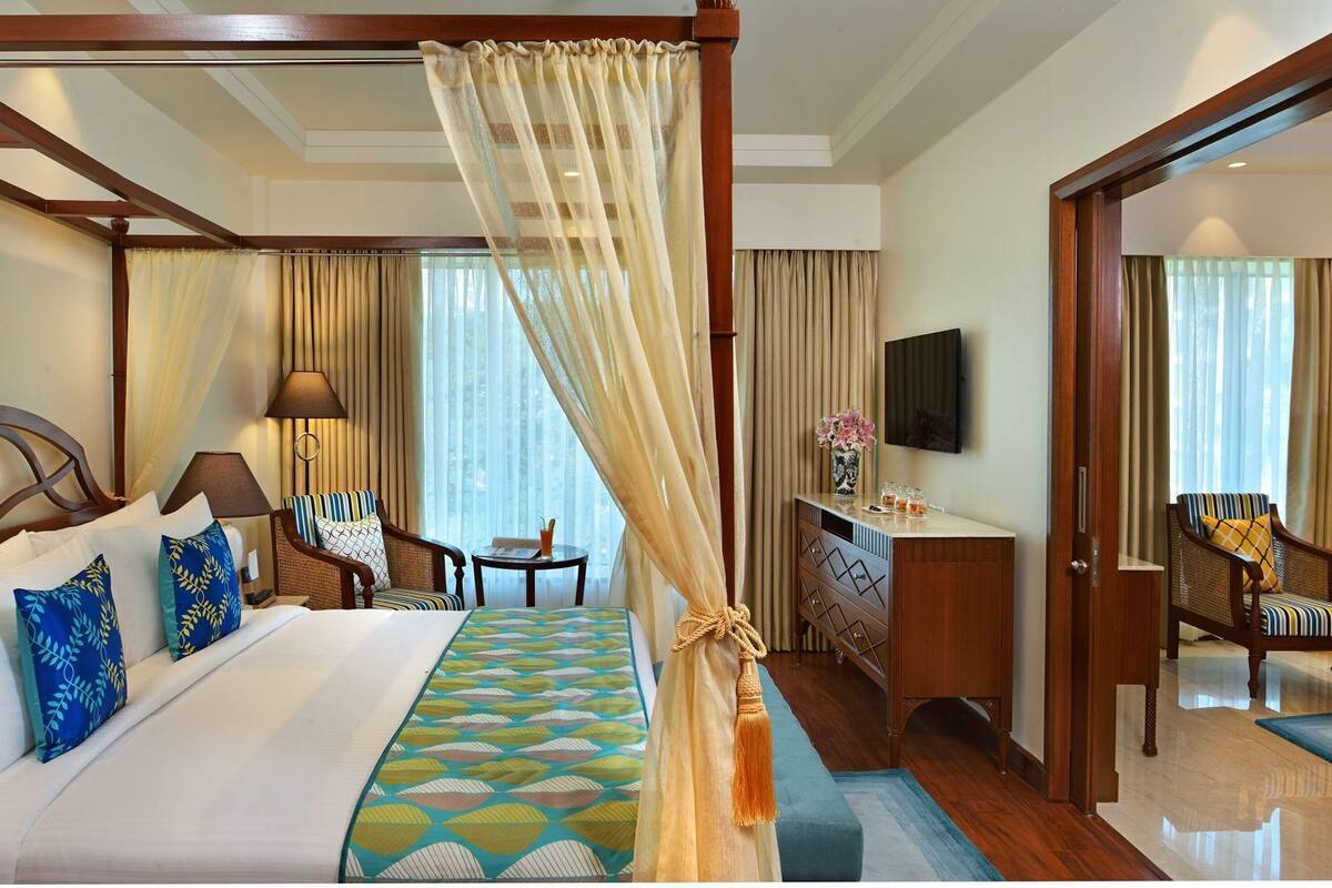 Une chambre d’hôtel avec un lit, un bureau, une chaise, une télévision et une grande fenêtre avec des rideaux.