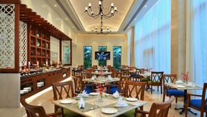 Uma ampla área de refeições com várias mesas, um buffet e uma tela de televisão.