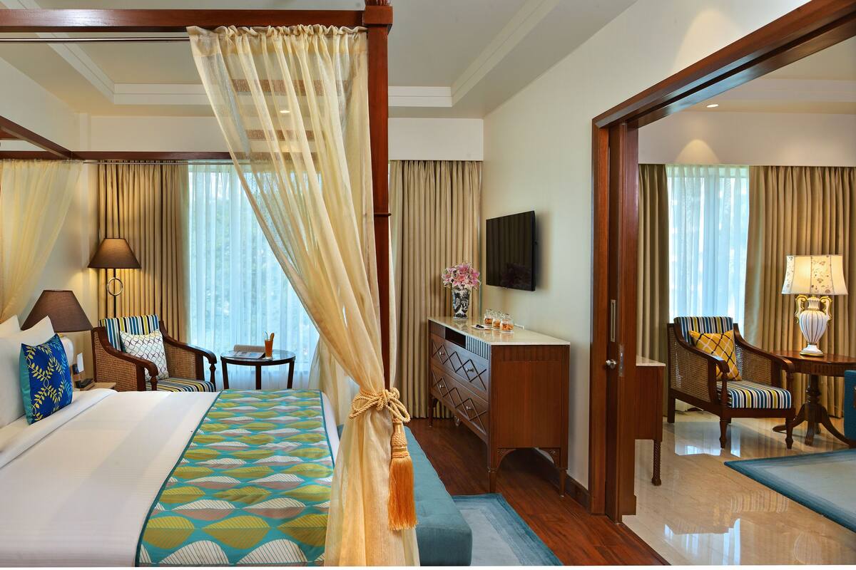 Une chambre d’hôtel avec un grand lit, un coin salon comprenant une chaise et une table, une commode et un téléviseur.