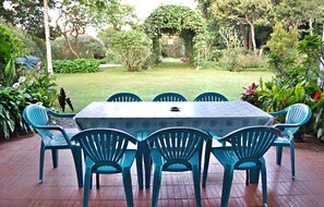 A patio with a table and chairs, surrounded by lush greenery and a well-maintained lawn.