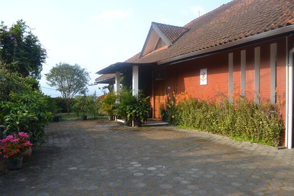 A building with a tiled roof, a brick facade, and a paved entrance area with potted plants.
